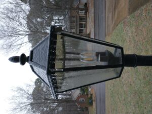 glaze of ice and small icicles hanging from the top edge of a yard lamp